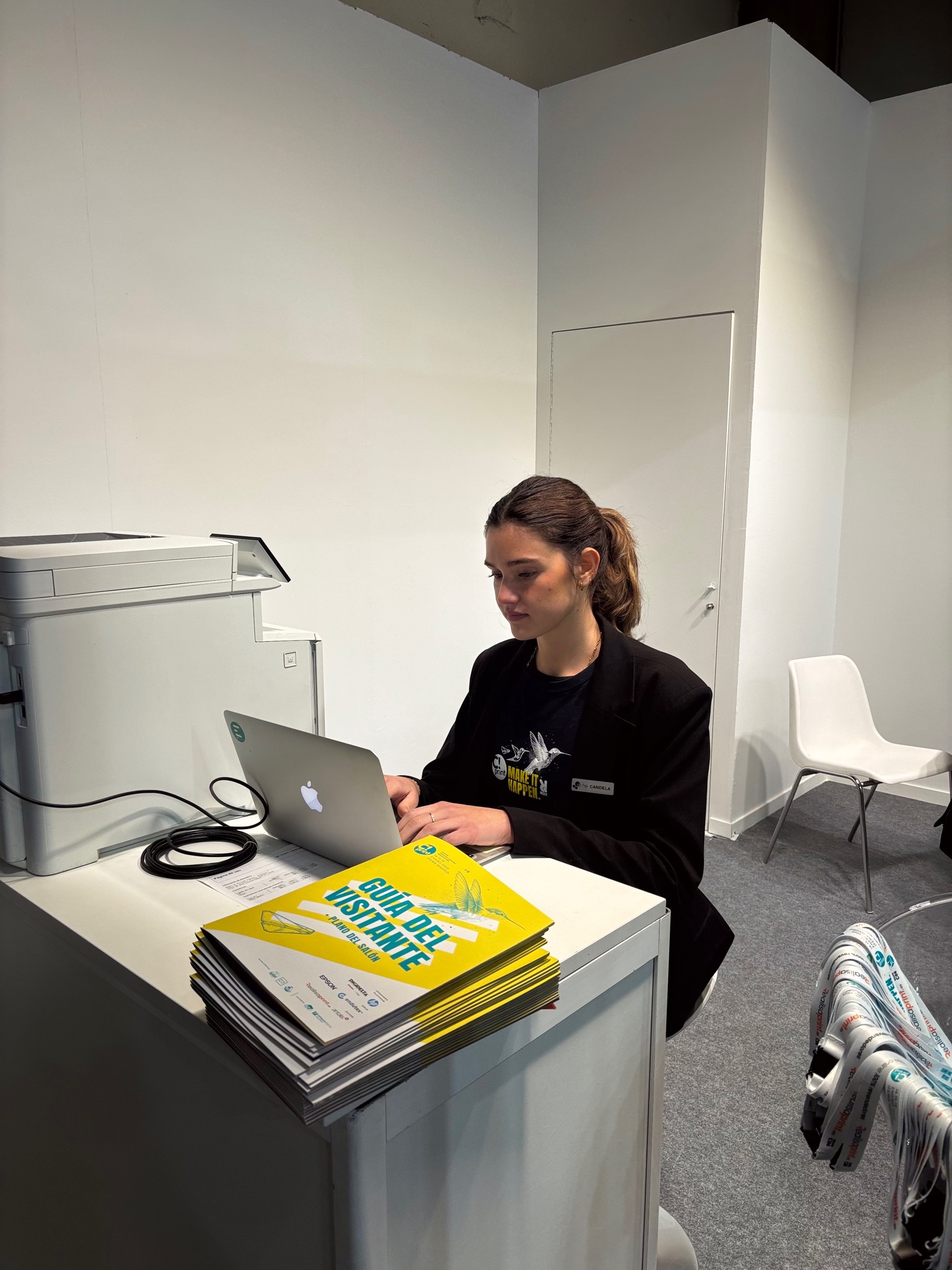 Azafata de ACHE Azafatas atendiendo en un mostrador de información en una feria profesional.