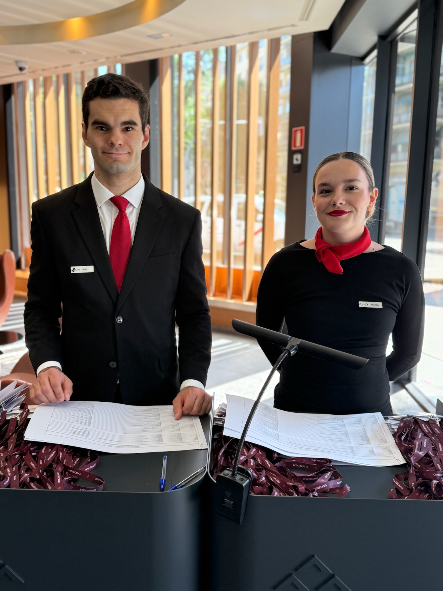 Azafatas/os bilingües facilitando la comunicación en un evento internacional, mostrando la importancia del personal bilingüe en entornos multiculturales.