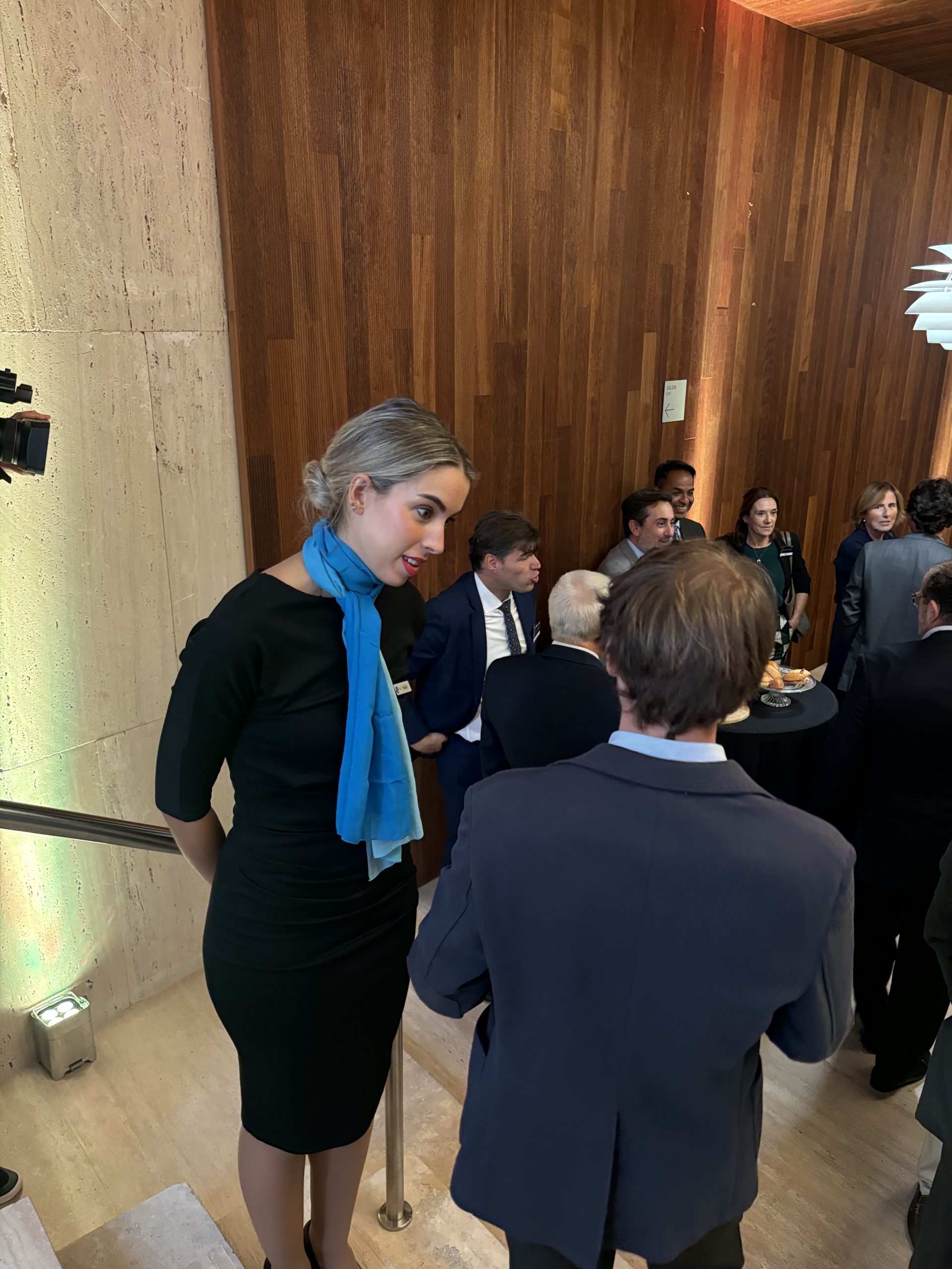 Azafata profesional atendiendo a un invitado en evento corporativo